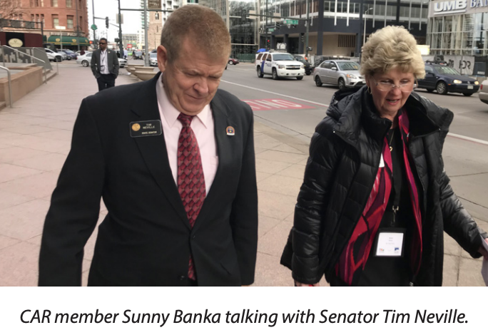 Source caption: CAR member Sunny Banka talking with Senator Tim Neville.